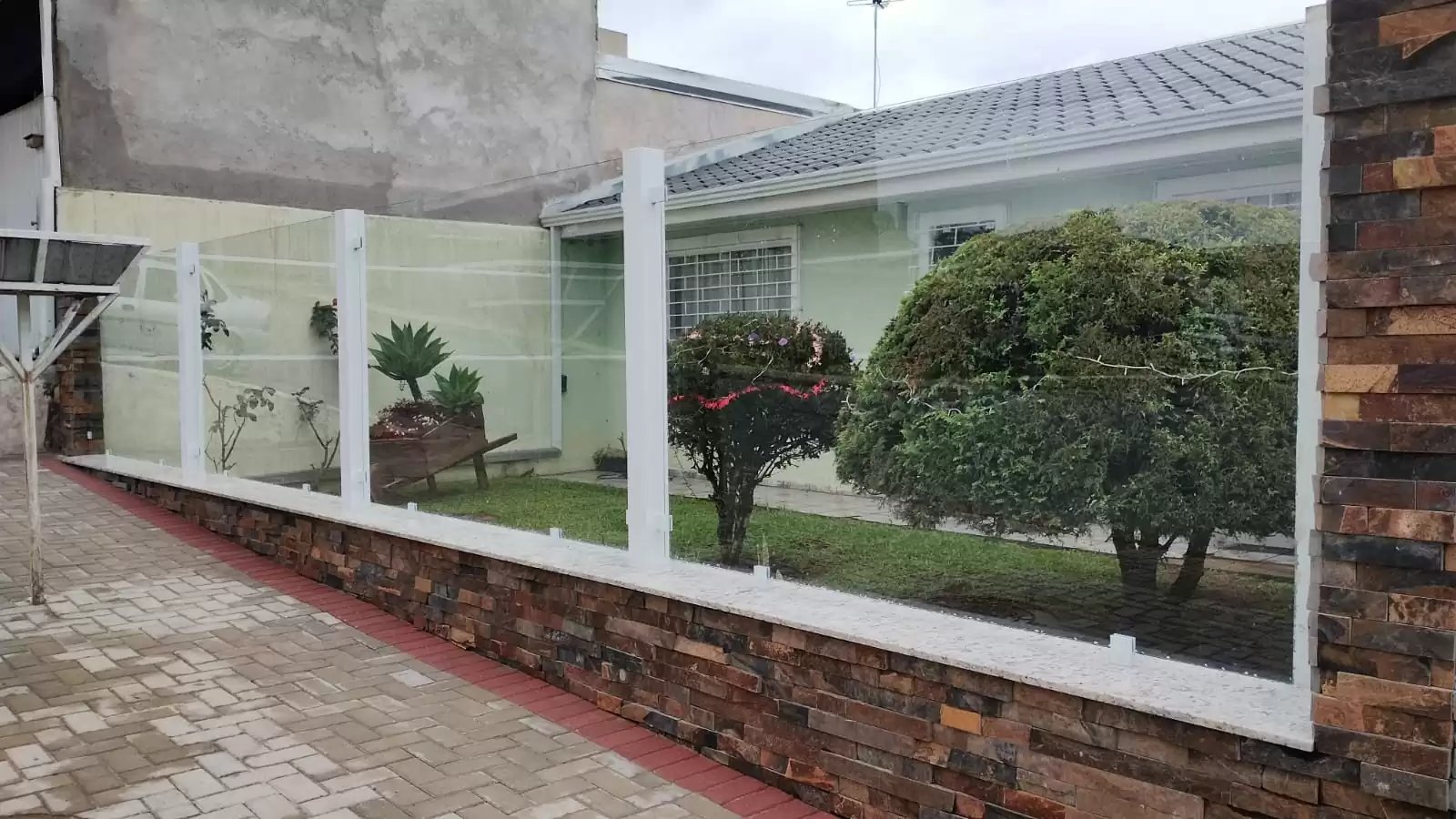 Muro de vidro transparente integrado ao paisagismo de uma residência
